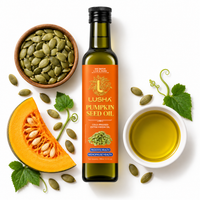 A bottle of Lusha Pumpkin Seed Oil centered on a white background, surrounded by pumpkin seeds, a sliced pumpkin, green leaves, and a small white cup of golden oil. The bottle has an orange label and is photographed in a clean, styled flat-lay composition.